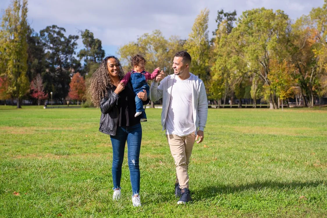 Parents and their child enjoying a walk together in a sunny park